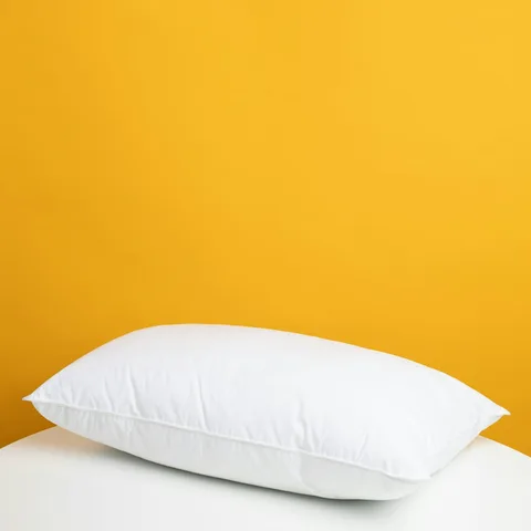 Crisp linen pillow against a marigold wall