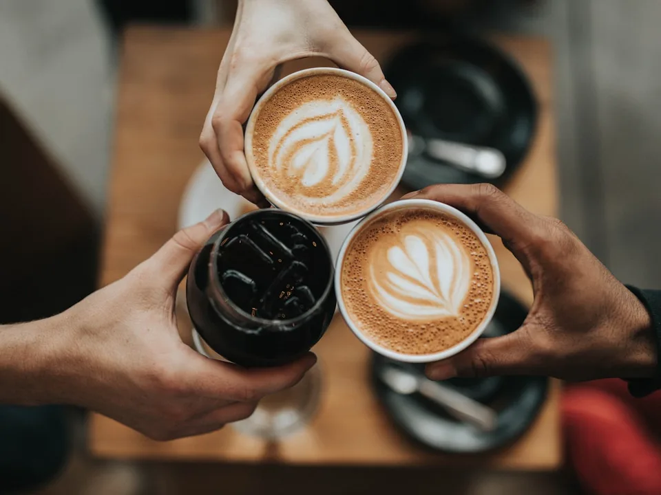 Flat whites raised in a toast at the bar