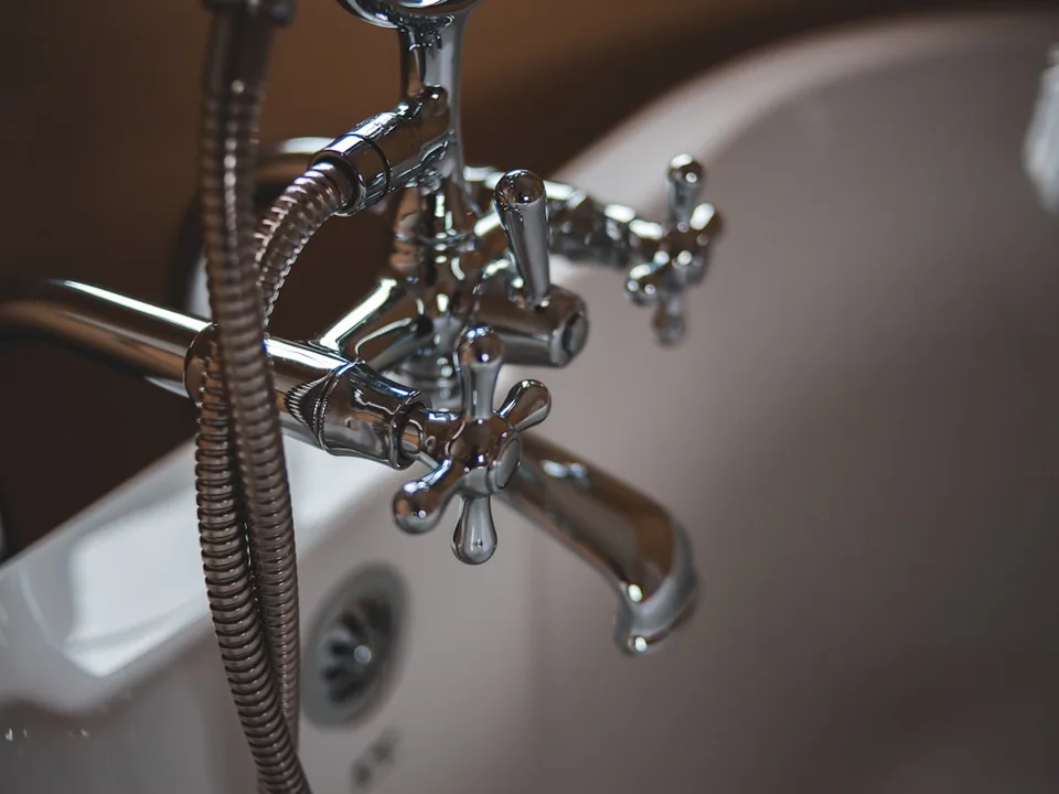 Plumber repairing a leaking pipe under a sink