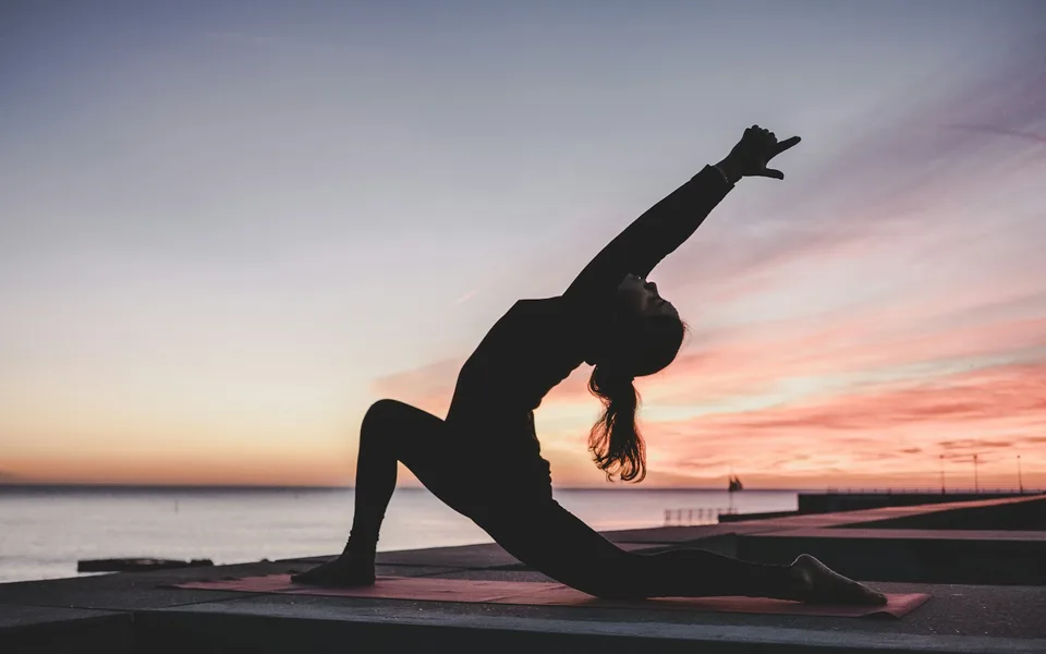 A practitioner in a seated pose as the sun rises